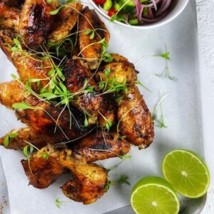 Chicken wings on a tray with lime wedges