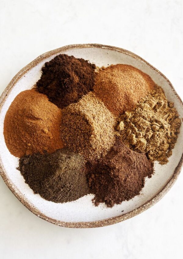 7 spices piled onto a plate on white background