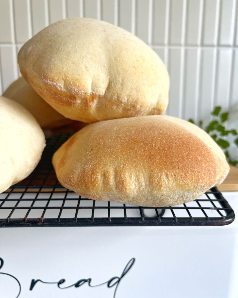 Pita Breads on a wire rack on a bread tin top