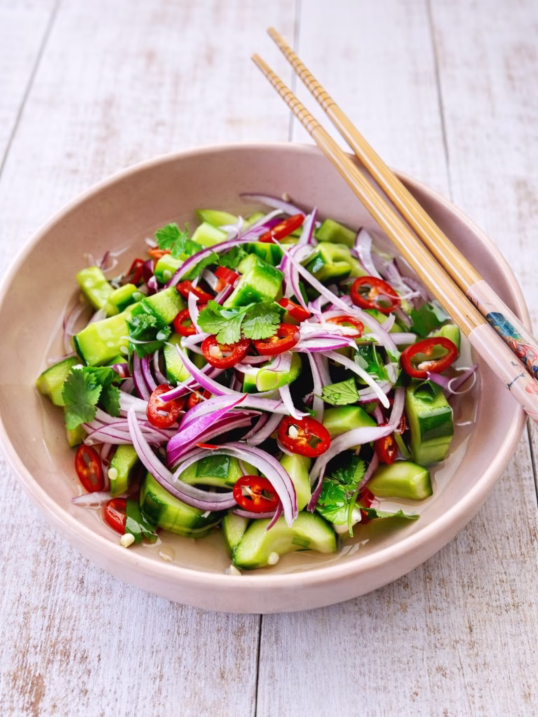 quick pickled cucumber salad in a pink bowl, white timber background.