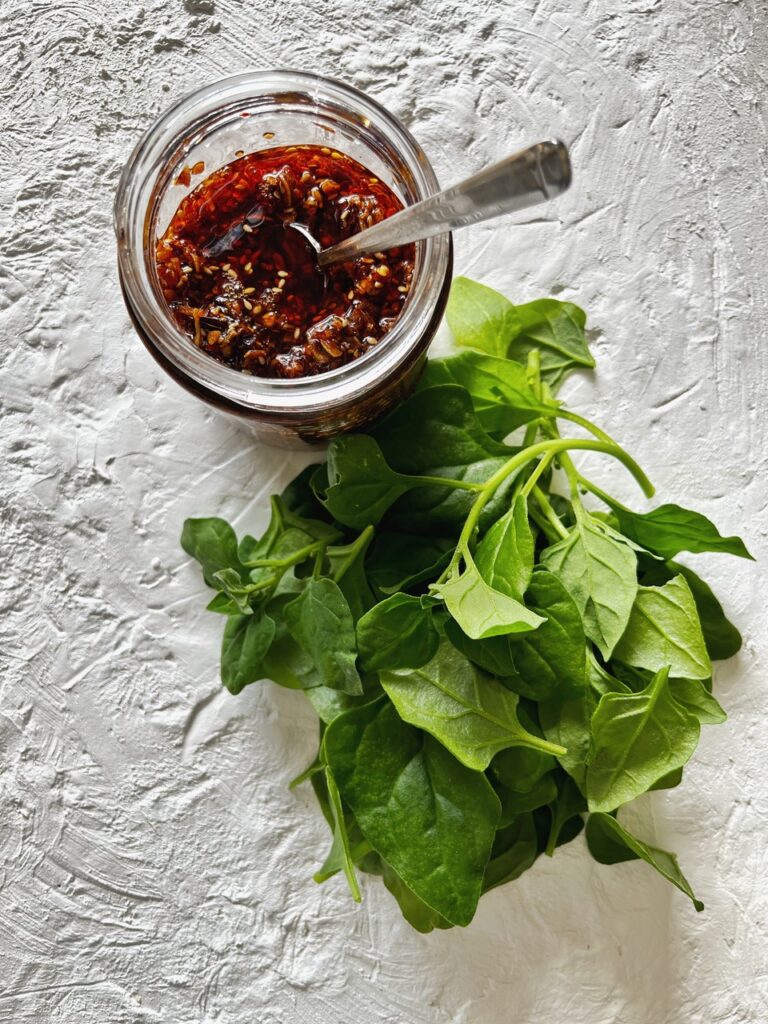 warrigal greens and chilli garlic crisp oil on white textured background