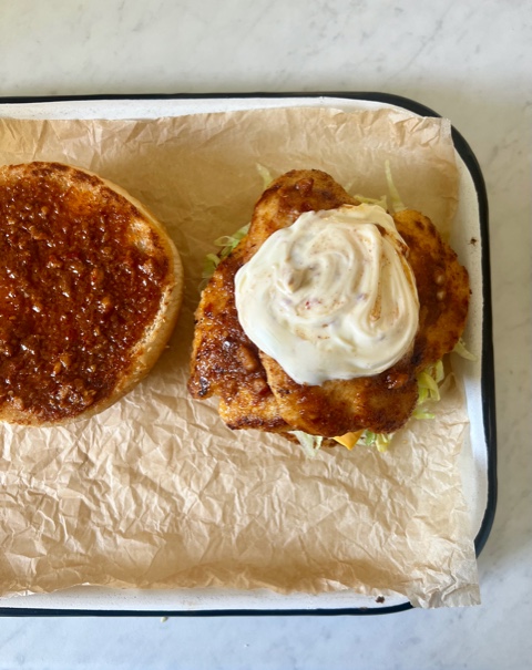 Burger bun top and bottom side by side with previous filling ingredients