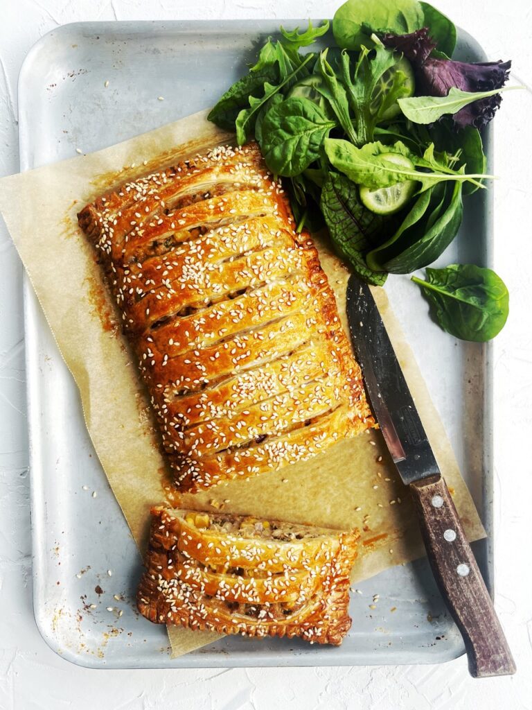 sliced tuna jalousie on baking tray with knife and salad leaves