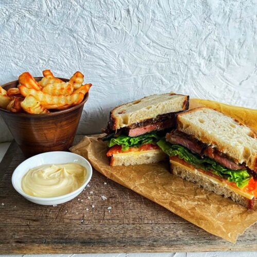STEAK SANDWICH ON BOARD WITH CHIPS AND MAYO