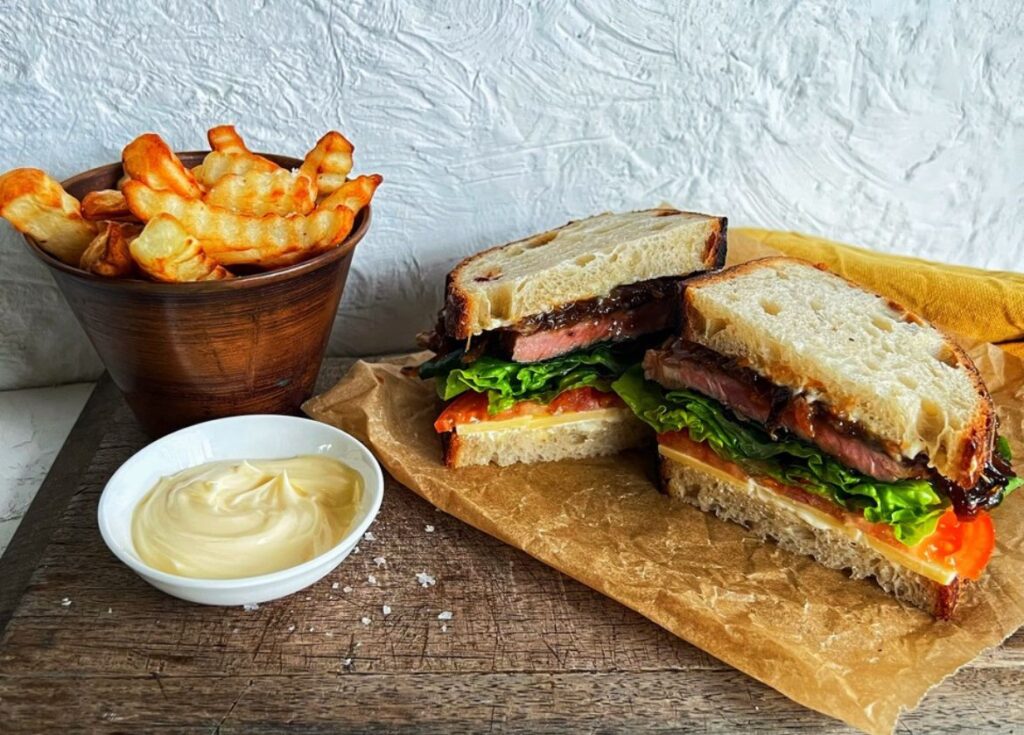 STEAK SANDWHICH ON BOARD WITH CHIPS AND MAYO