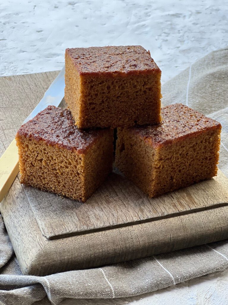STICKY GINGER CAKE CUT INTO SQUARES ON OLD CHOPPING BOARD WITH BONE HANDLED KNIFE