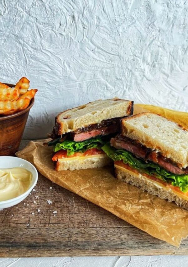 STEAK SANDWICH ON BOARD WITH CHIPS AND MAYO
