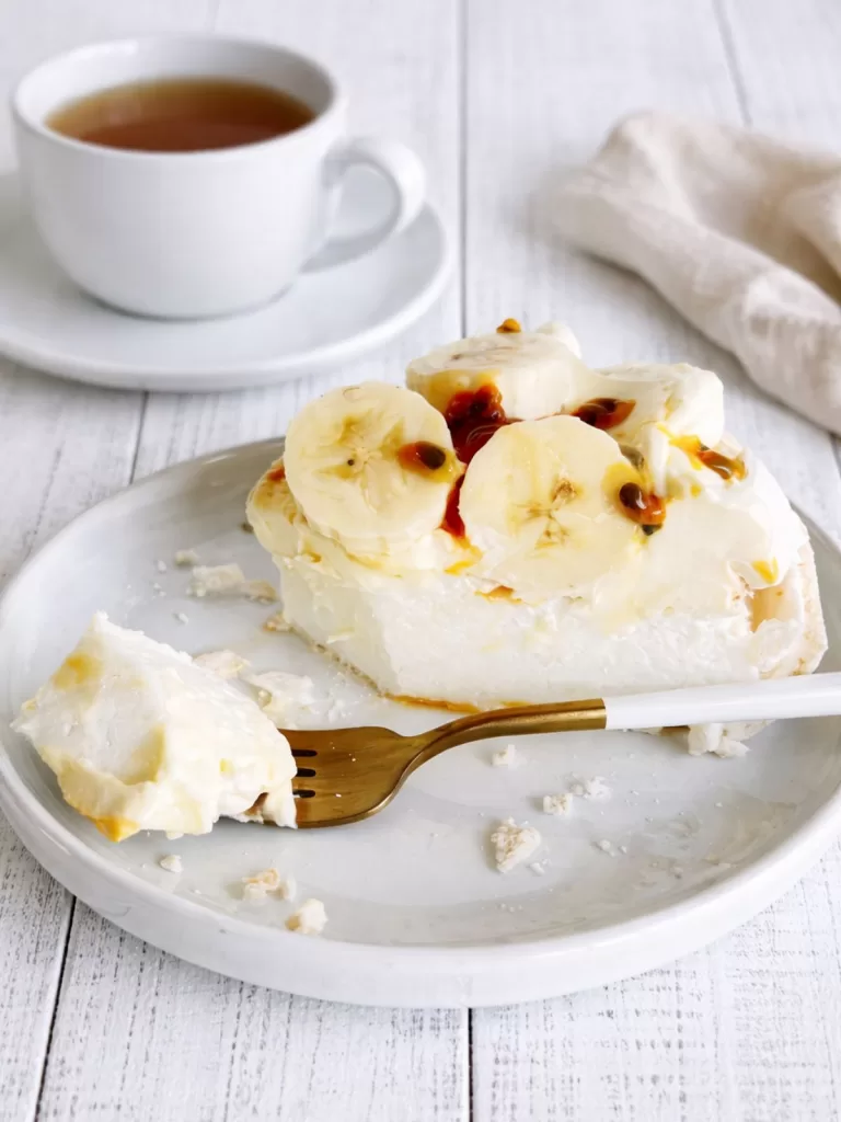 Slice of easy pavlova on a white plate with fork half eaten