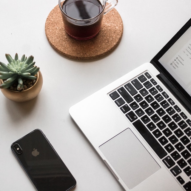 Laptop, mobile phone, plant and coffee on a desk top