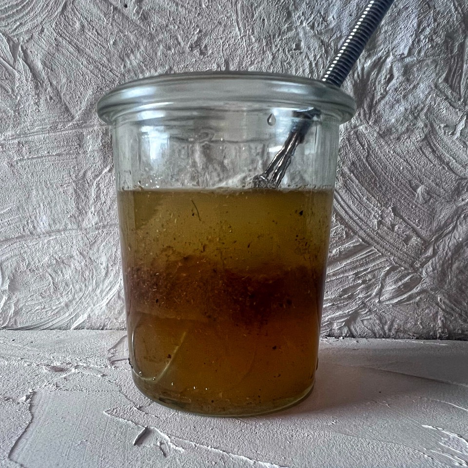 Honey lime dressing in a small glass jar with a whisk in it