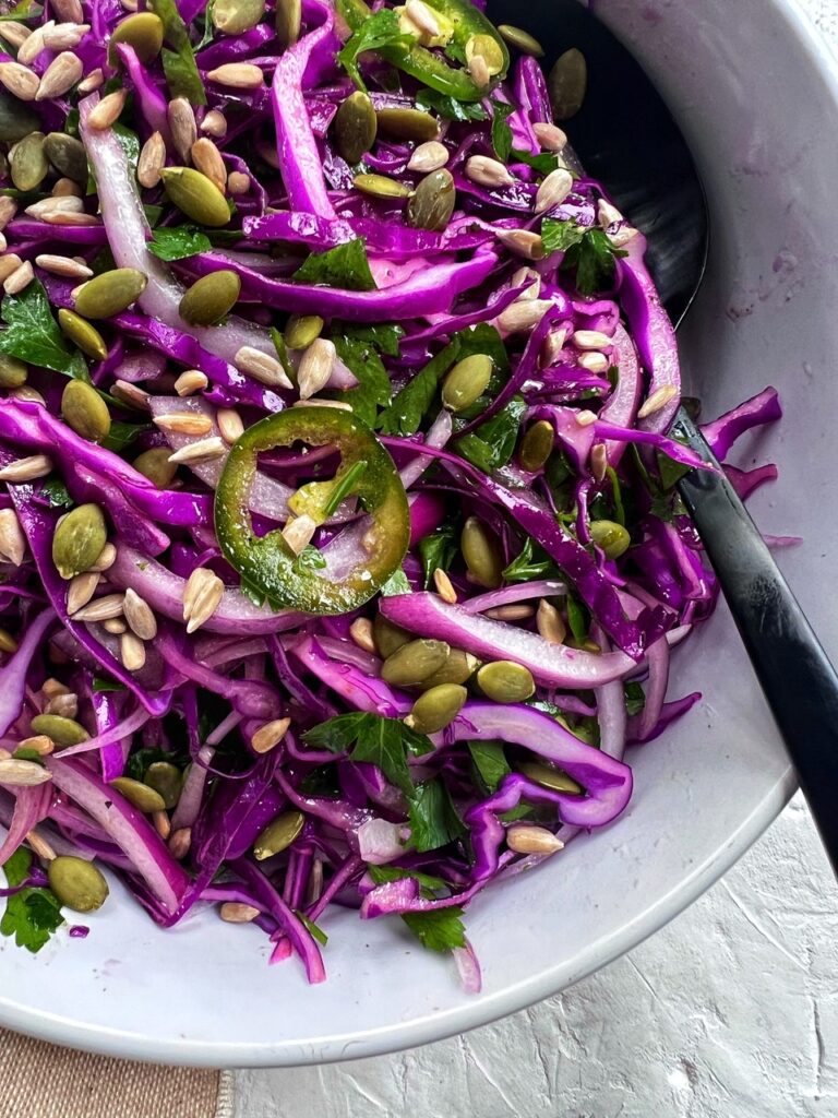 red cabbage salad in bowl with a serving spoon