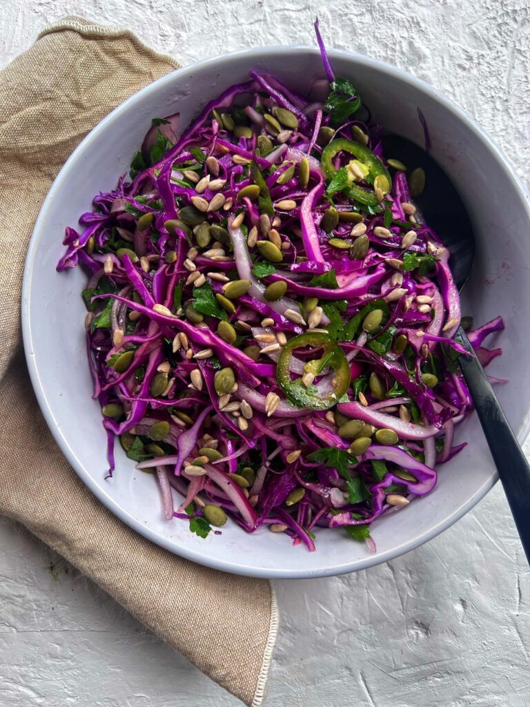red cabbage salad in bowl with a serving spoon