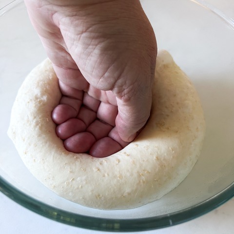 Punching the pita bread dough down in a bowl with my hand