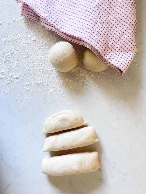 Pita bread cut into pieces ready to be rolled. Some already rolled under a tea towel