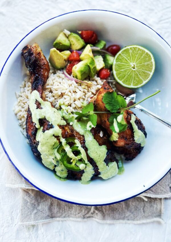 Peruvian Chicken with Green Sauce in a bowl with avocado salsa, brown rice and lime. Napkin underneath the plate
