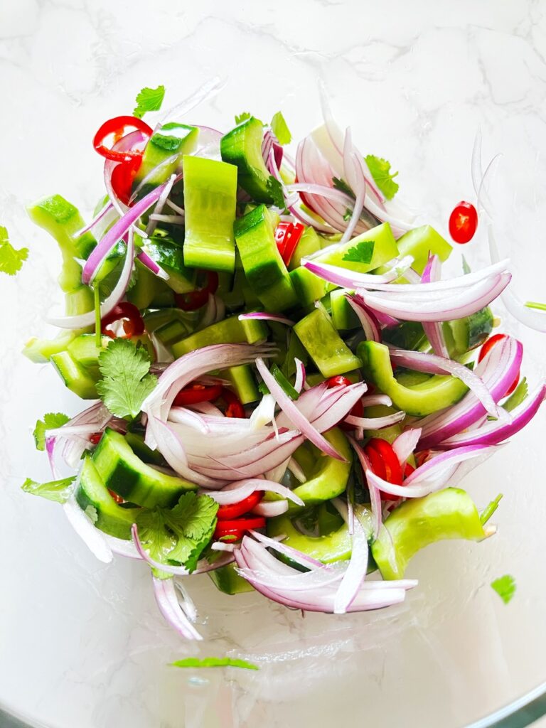 close up of quick pickled asian cucumbers in glass bowl