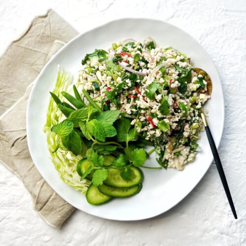 Thai Chicken Larb Salad on plate with assorted green vegetables to serve with it.