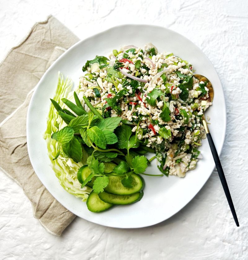 Thai Chicken Larb Salad on plate with assorted green vegetables to serve with it.