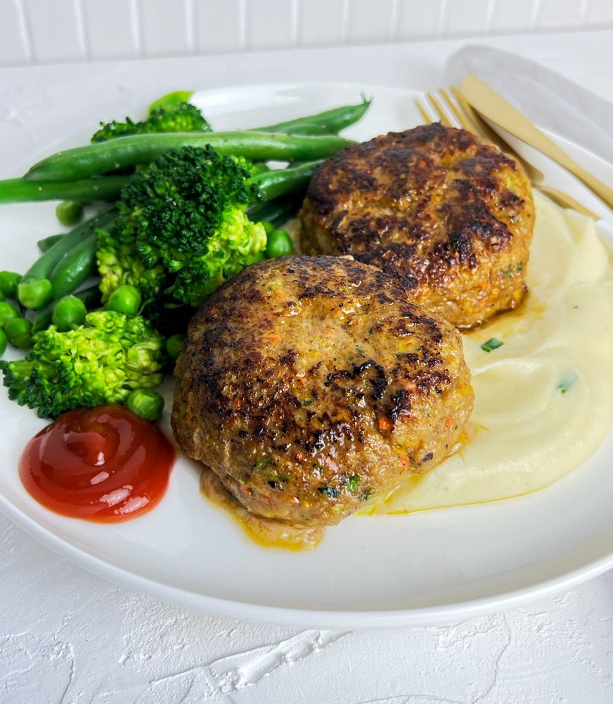 rissoles with mash and vegetables on white plate. Tomato sauce 'ketchup' on the side