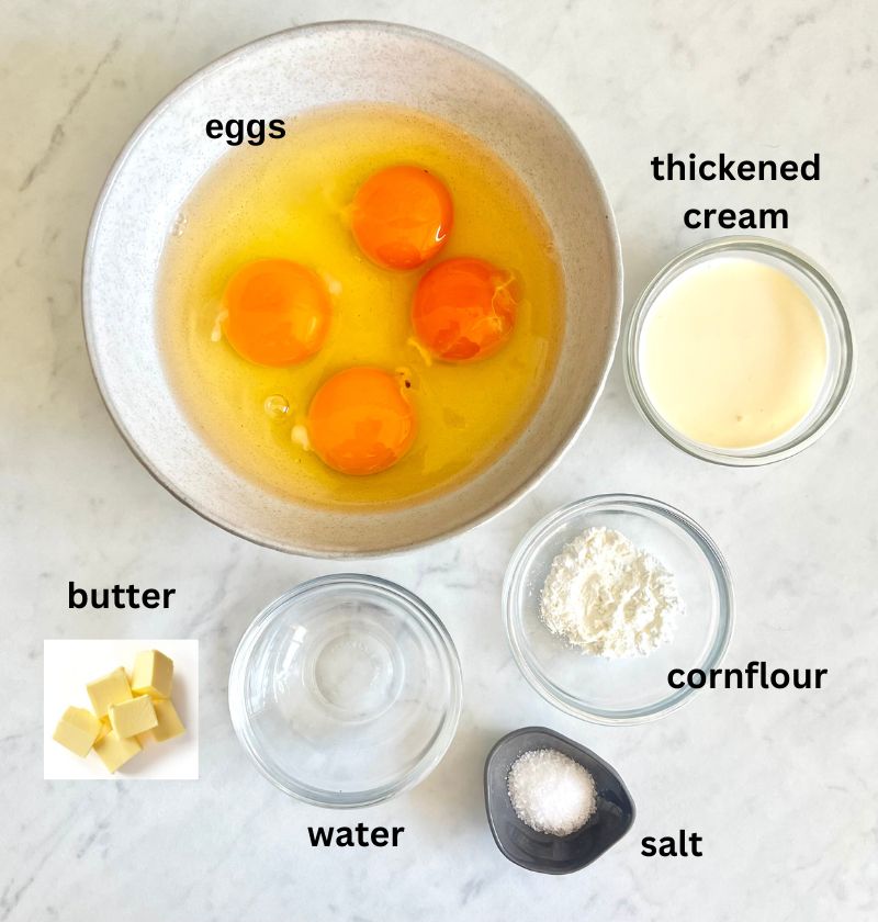 scrambled eggs ingredient board. Eggs, thickened cream, butter, water, corflour and salt. All ingredients are in separate bowls with the text word written above each one.