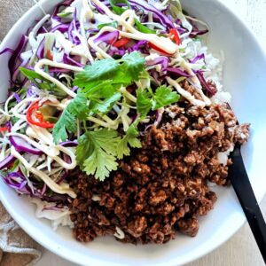 Asian beef bowls in white bowl with black fork to the side