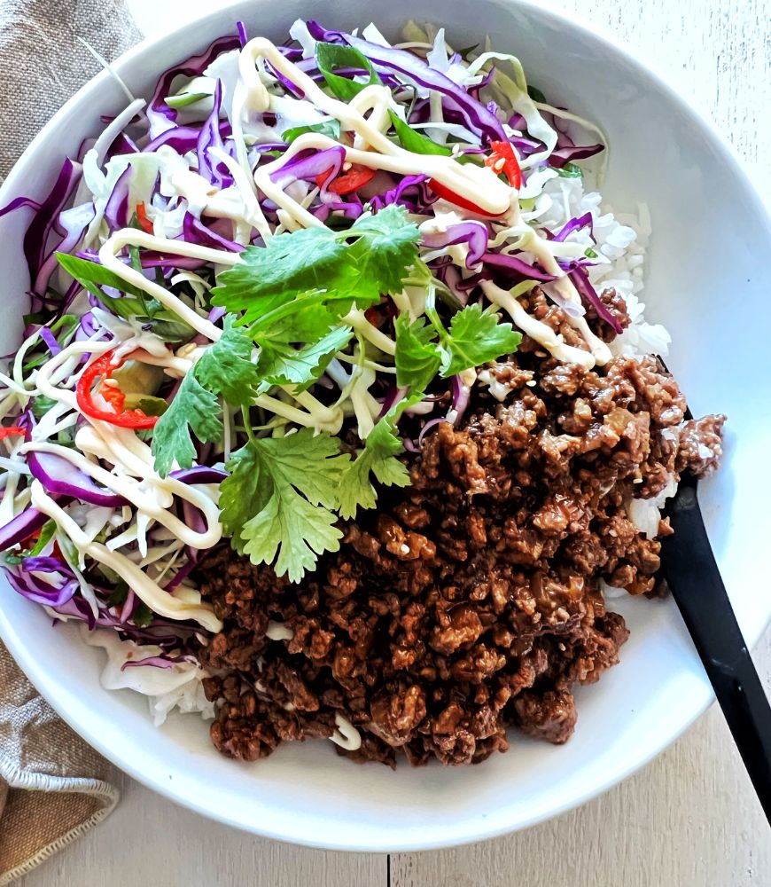 Asian beef bowls in white bowl with black fork to the side