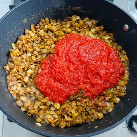 onion, spices and diced tomatoes cooking in a pan
