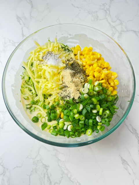 grated zucchini, corn, cheese, spring onions and spices in a bowl