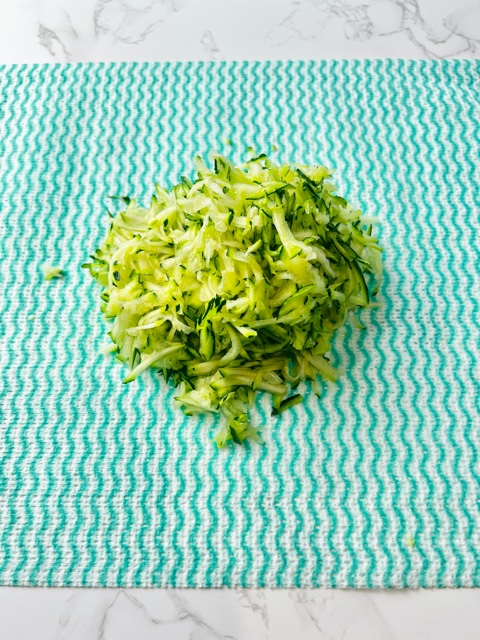 grated zucchini sitting on a green kitchen cloth