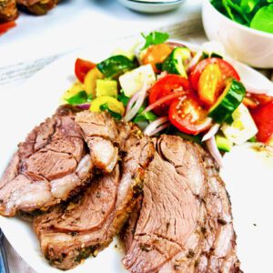 Greek Boneless Lamb Leg sliced on a white plate with Greek Salad