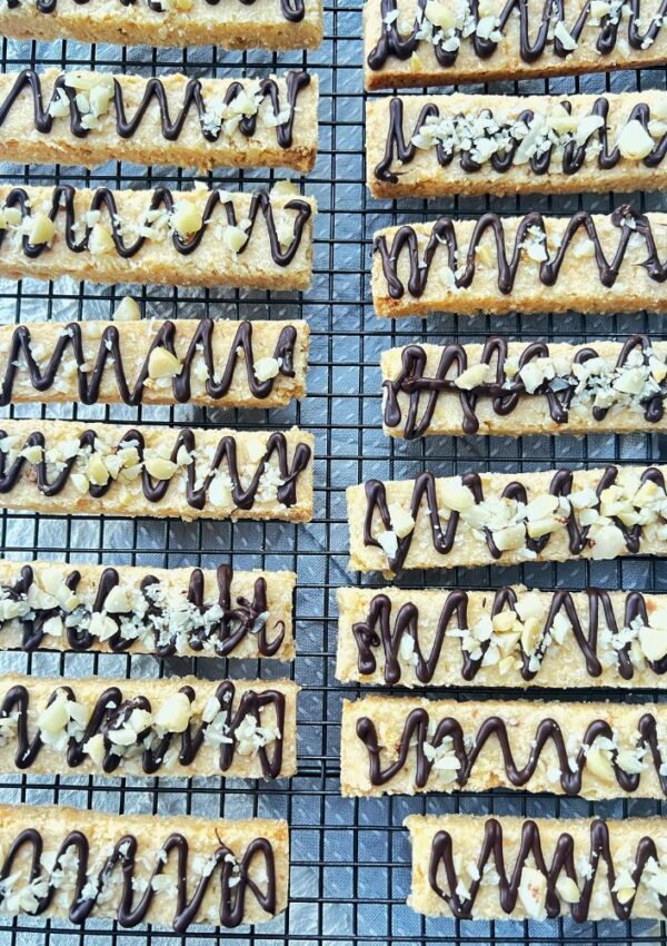 Shortbread fingers on a wire baking tray lined up with chocolate drizzled over