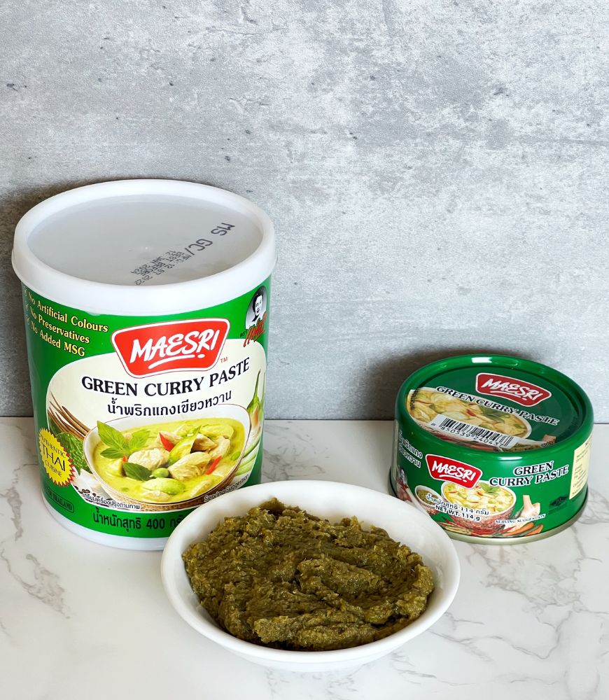 MAESRI GREEN CURRY PASTE IN A TUB, A CAN AND SOME SCOOPED ONTO A SMALL WHITE BOWL.