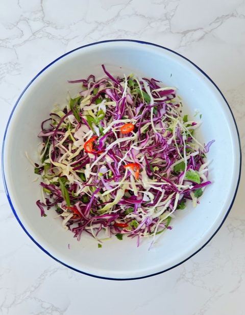 dry coleslaw mixture in white enamel bowl on marble bench top