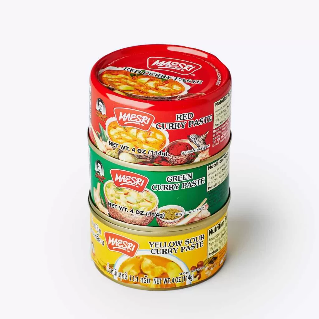 Maesri Thai curry pastes including red, green and yellow curry paste tins stacked on a white background