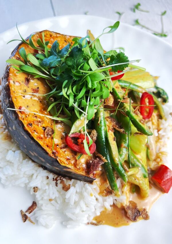 Thai Red Pumpkin Curry. Pumpkin wedge on plate with rice, beans, bok choy, chilli and coriander