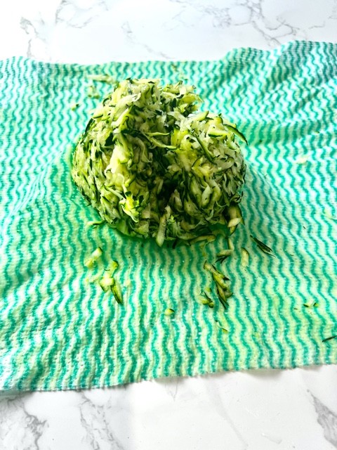 zucchini grated and squeezed sitting on a green kitchen cloth