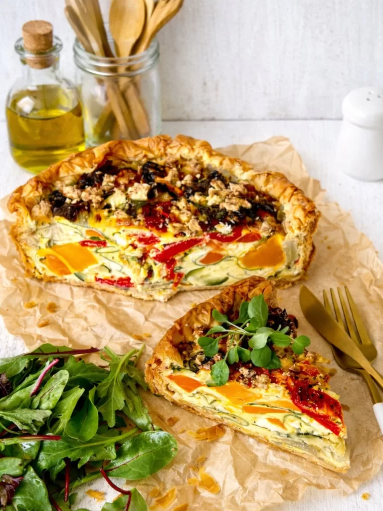 roasted vegetable quiche on baking paper, white background.