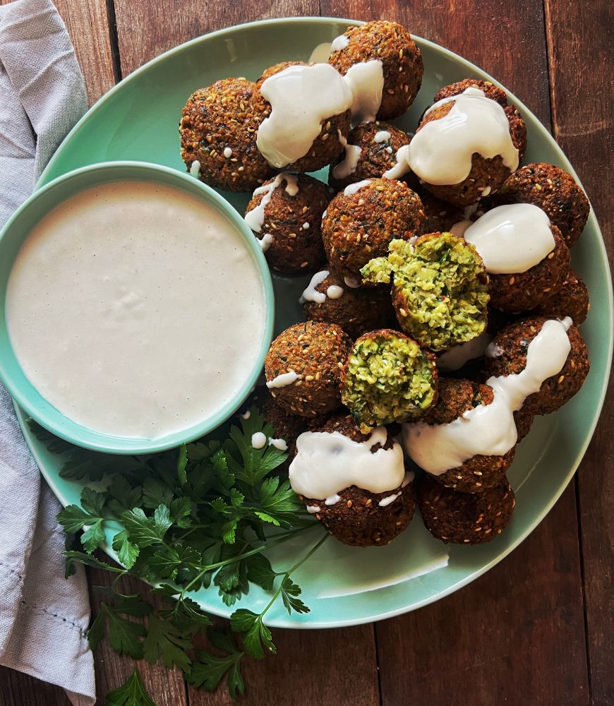 falafels on a plate with tahini dipping sauce and parsley
