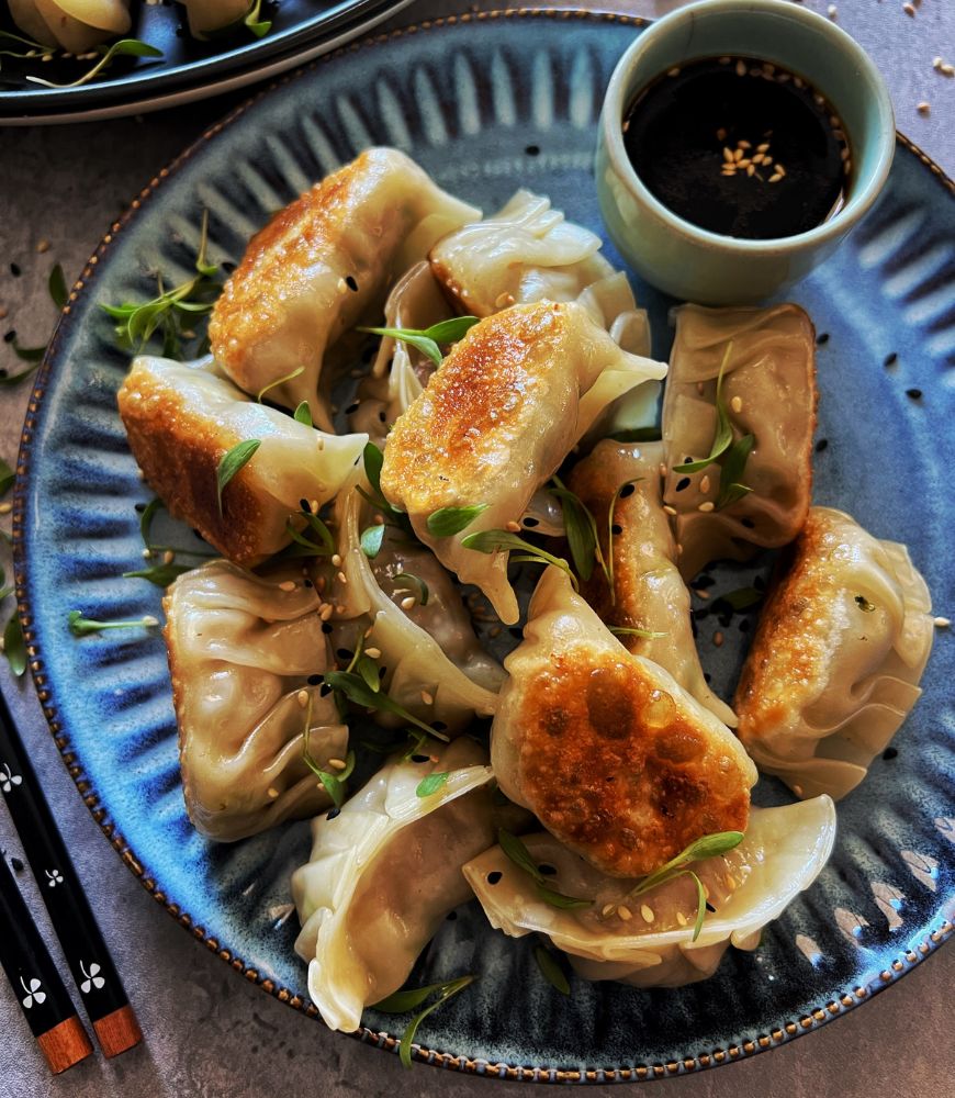 PORK DUMPLINGS ON A BLUE PLATE WITH DIPPING SAUCE