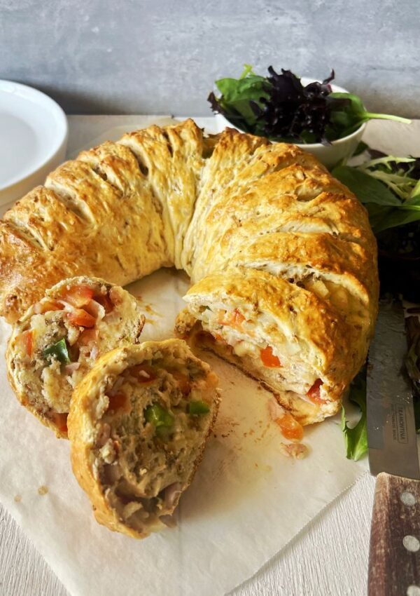 Cheese Crescent on baking paper with salad leaves and a knife