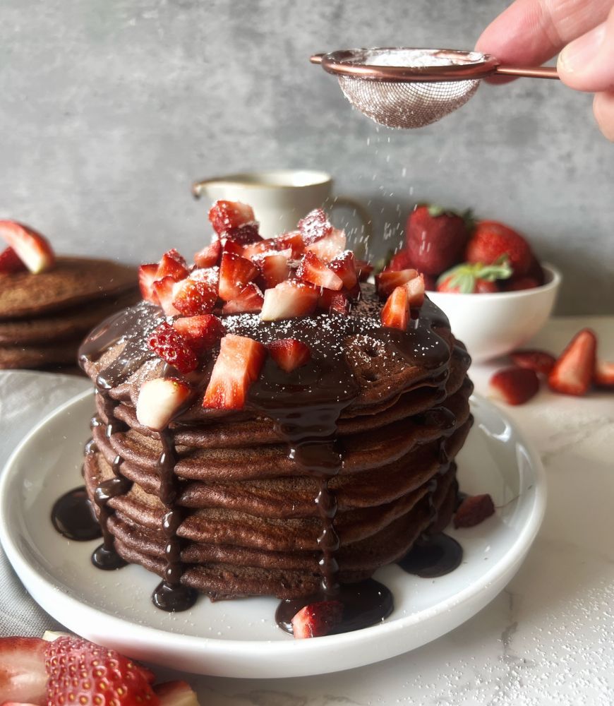 dusting chocolate buttermilk pancakes with icing sugar