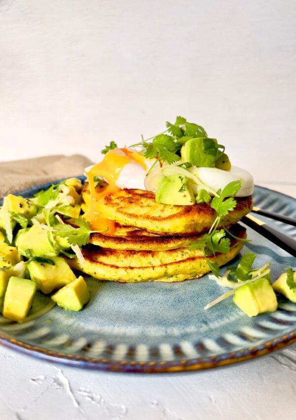 CORN FRITTER STACK WITH AVOCADO SALSA AND POACHED EGG ON BLUE PLATE