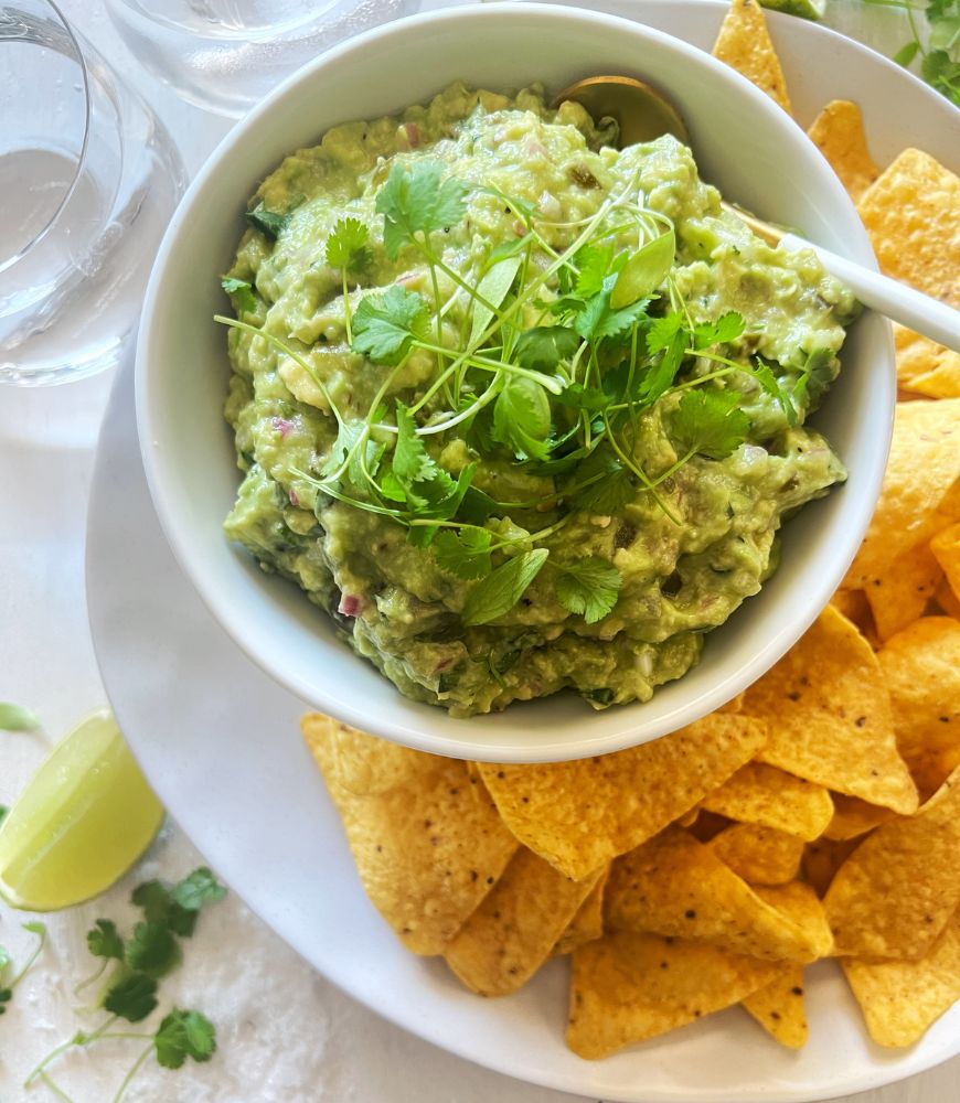 guac in a white bowl with corn chips