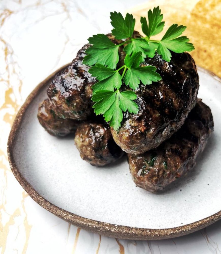 Lamb Kofta (Kafta) stacked on a ceramic plate garnished with parsley