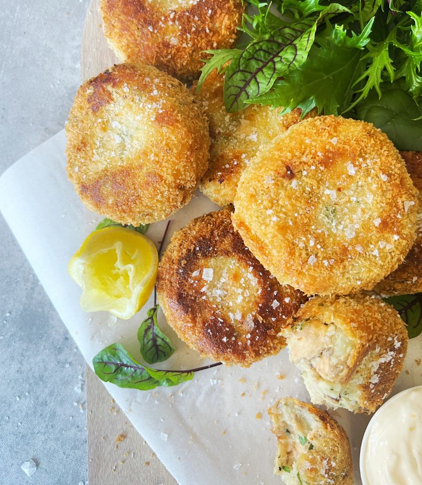 fish cakes on baking paper with lemon and salad