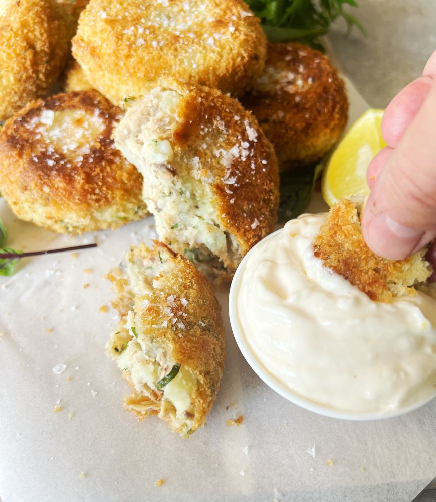 dunking a salmon cake in lemon aioli