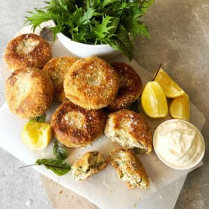 salmon & potato cakes on baking paper with green salad, lemon wedges and aioli