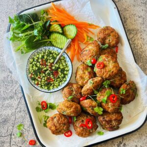 Thai pork cakes on white tray with vegetables and herbs