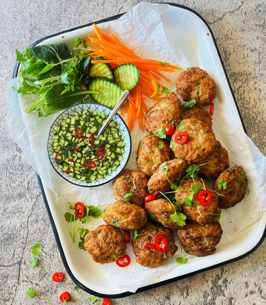 Thai Pork Cakes with Cucumber Dipping Sauce on white tray on concrete background. Chilli and coriander to garnish on top