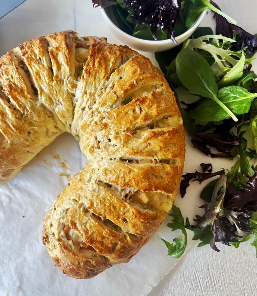 cheese crescent on baking paper with lettuce leaves around it